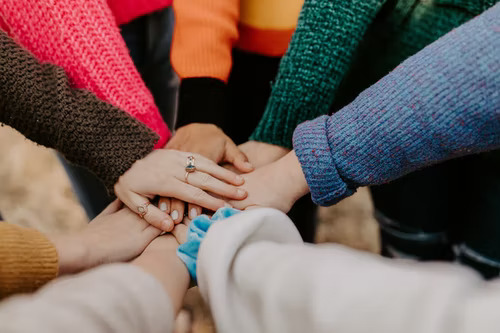 Manos reunidas en el centro representando una comunidad TikTok. 