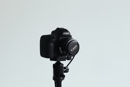 빈 배경 앞에 카메라 삼각대에 장착된 DSLR 캐논 카메라.