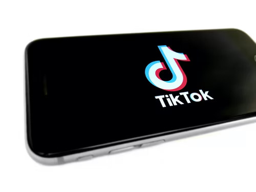 Mobile phone with TikTok logo and a black background on the screen.