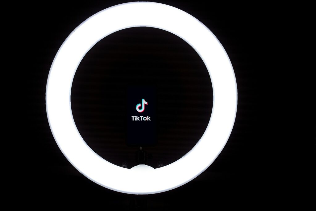 TikTok’s musical note logo and brand name are centered inside a ring light. 