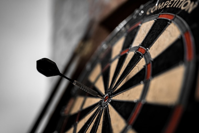 A dart hitting the middle of a dart board. 