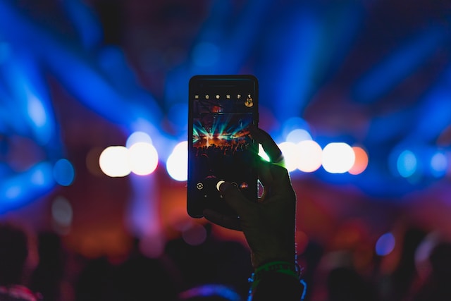 Une personne qui filme un spectacle en direct à l'aide de son téléphone. 