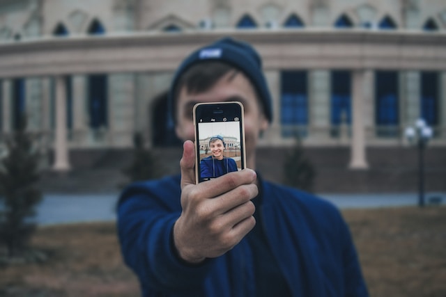Uma pessoa gravando um vídeo de si mesma usando seu telefone. 