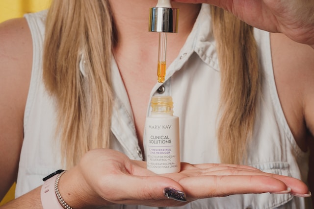 A woman holding a bottle of skin serum.