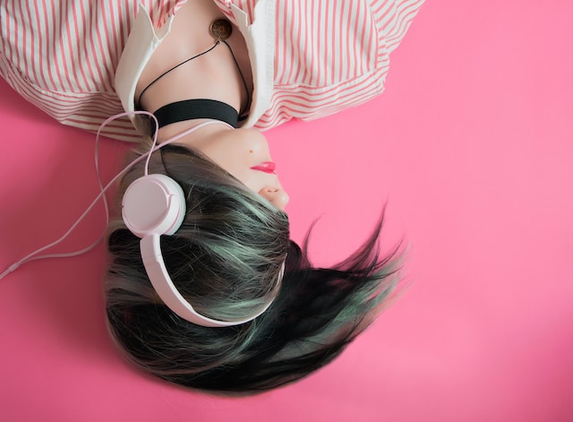 Een vrouw luistert naar muziek met een witte hoofdtelefoon. 