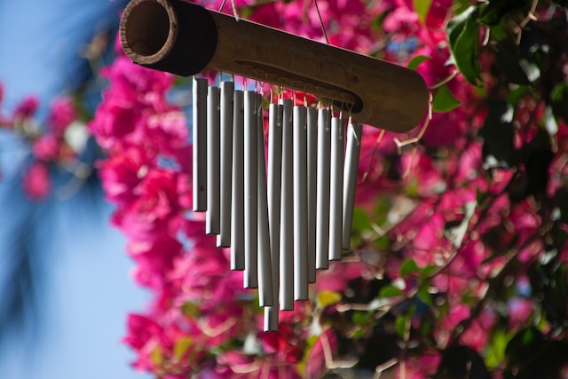 Een metalen windgong die aan een boom hangt. 