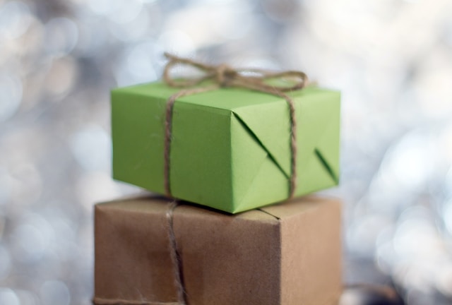 Ein Stapel mit Geschenken, eingewickelt in grünes und braunes Papier. 