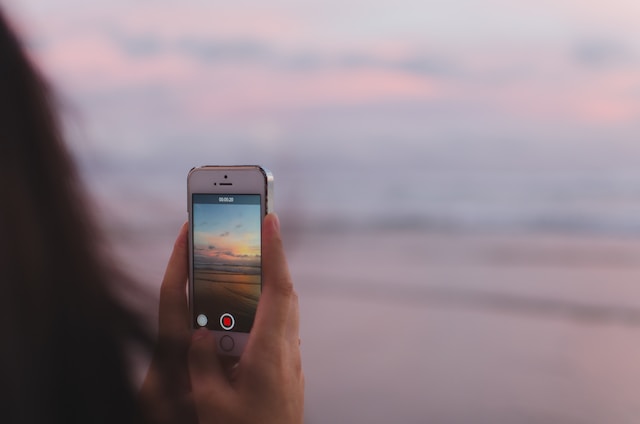 Iemand die de zonsondergang vastlegt met zijn telefooncamera. 