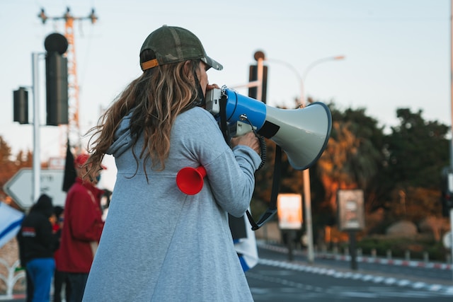 Una mujer hablando por un altavoz antiguo. 