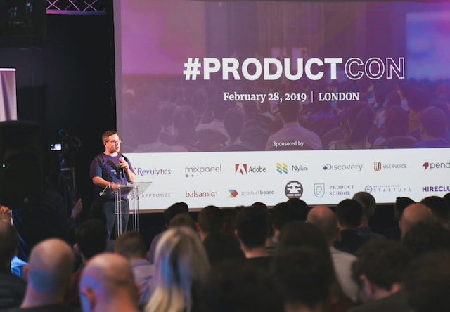 A speaker presenting in front of a big audience.