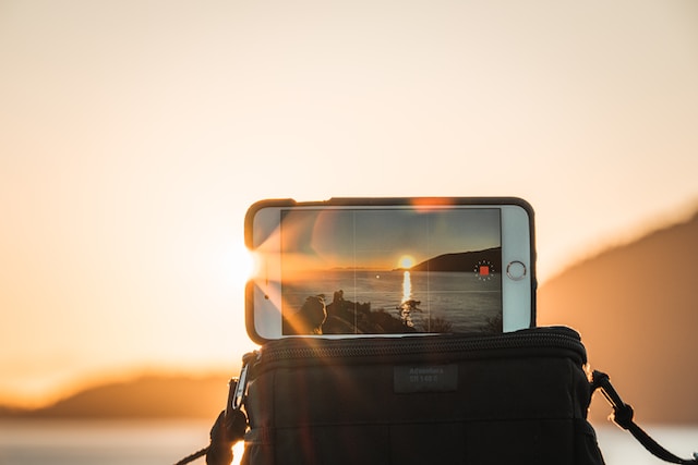 用手机拍摄日落的人。  
