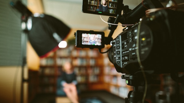 Een DLSR-camera neemt een vrouw op in een bibliotheek. 