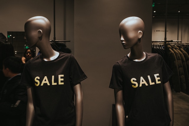两个人体模型穿着印有 "特卖 "字样的黑色衬衫。 