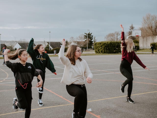 A group of girls practicing a dance in a parking lot. 