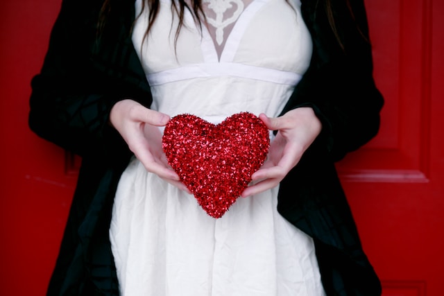 A woman holding a sparkly heart pillow. 