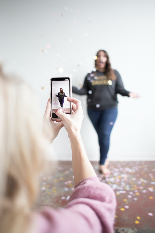 A girl posing for a TikTok video being recorded. 