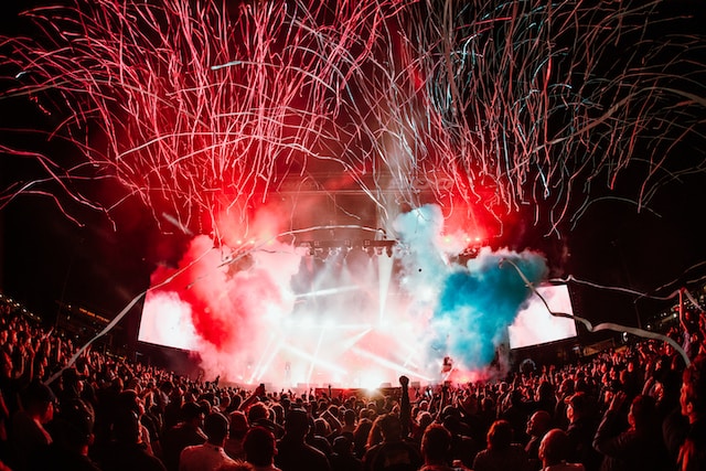 Un grande pubblico assiste a uno spettacolo di luci durante un evento all'aperto. 