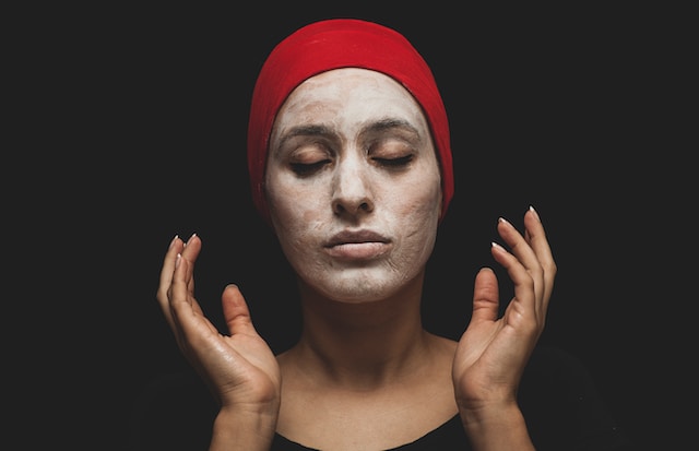O femeie purtând o mască de argilă albă.