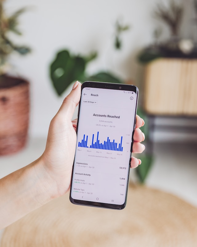 Een persoon met een telefoon in de hand die het aantal bereikte accounts laat zien. 