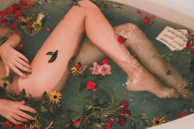 Een vrouw in een bad met bloemen drijvend in het water. 
