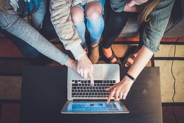 Een groep vrouwen leest online commentaar op een laptop. 