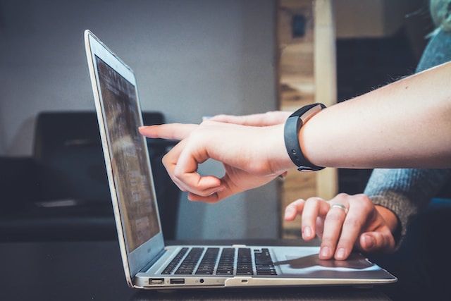 Two people looking at performance numbers on a laptop. 
