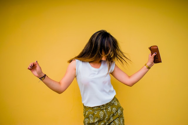 A woman dancing in front of a yellow wall. 