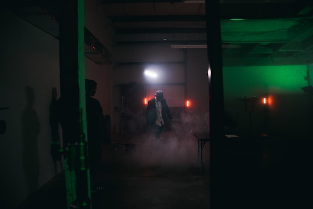 Two men filming in a dark room with a smoke effect on the floor. 