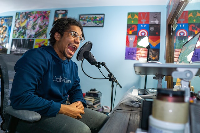 Un homme assis sur une chaise noire devant un microphone. 