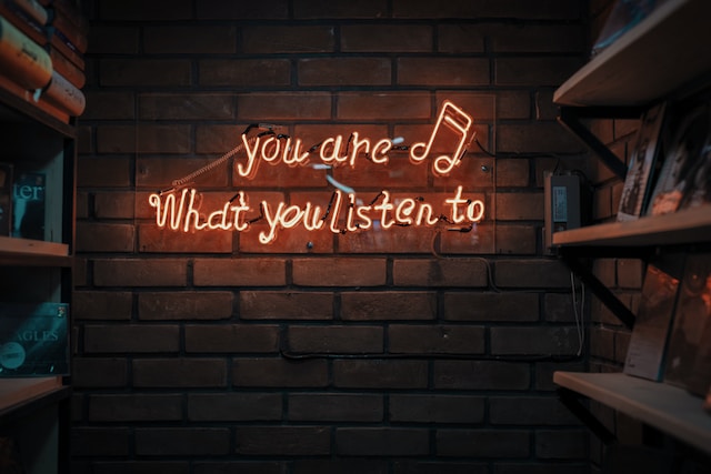 砖墙上的霓虹灯写着 "你听什么，你就是什么"。