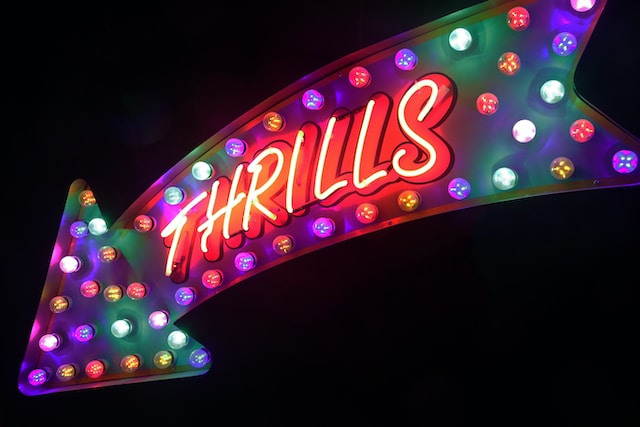 A big arrow with rainbow lights and the word “THRILLS.”