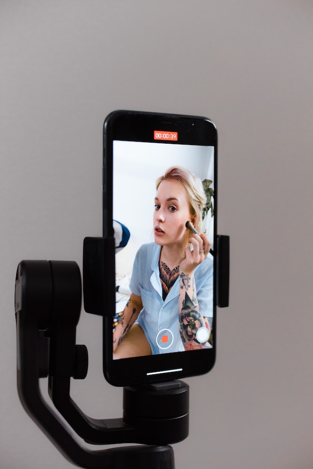  A girl recording a makeup video for Tik Tok on an Android phone.