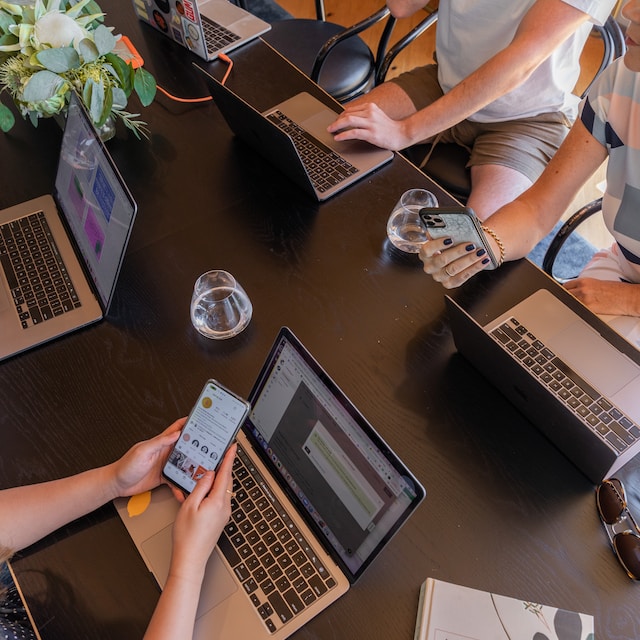 Een tafel met een groep mensen die met laptops zitten en hun sociale mediatrends observeren. 