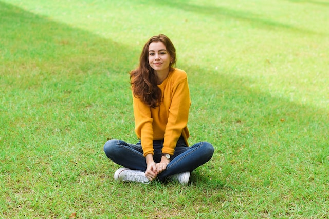 Ein Mädchen sitzt im Gras und posiert für ein Foto. 