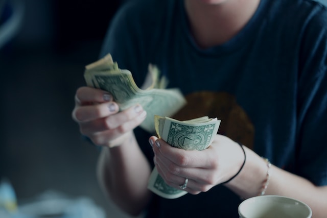 A person counting dollar bills. 