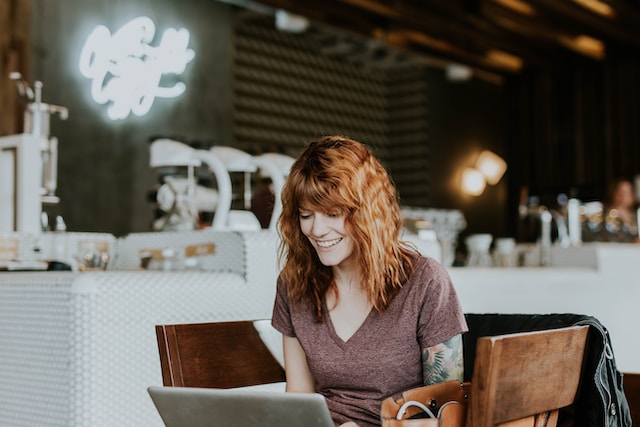 Een vrouw in een coffeeshop die haar laptop gebruikt. 