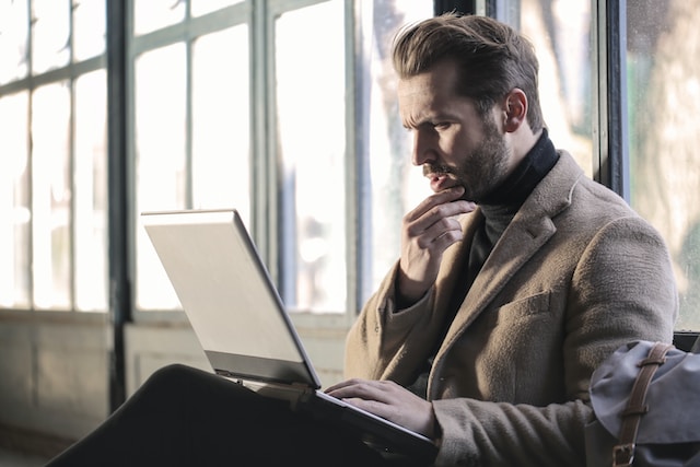 Um homem navegando em seu laptop. 