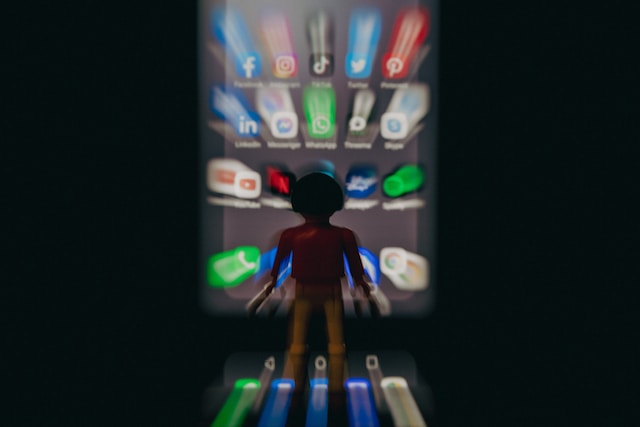 A blurry image of a person standing before a phone screen.