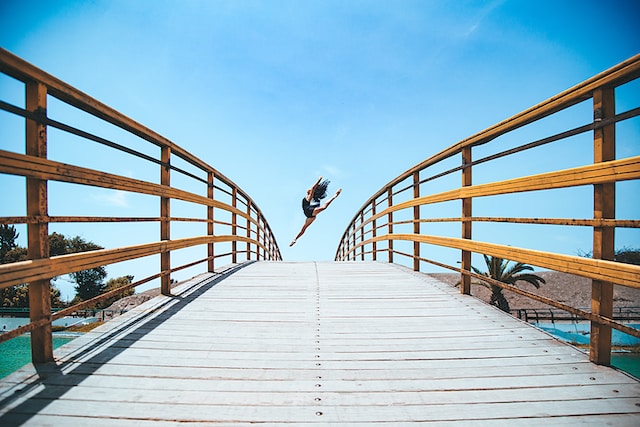 A woman leaping for a dance on a bridge. 