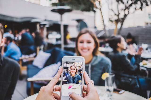 A person taking a video of a smiling woman to create content on TikTok.