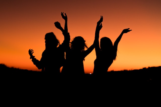 Três mulheres em silhueta ao pôr do sol. 