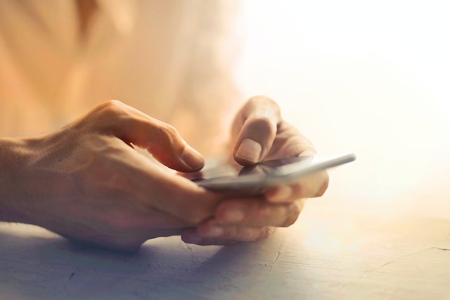 Eine lächelnde Frau, die eine Getränkedose in der Hand hält und vor ihrem Telefon steht, um Inhalte zu erstellen.