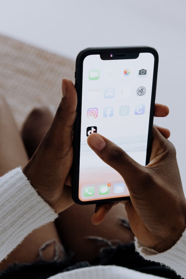 Une personne tenant un smartphone et cliquant sur l'application TikTok. 