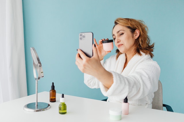 Una mujer que se hace una foto y utiliza TikTok para promocionar su marca y su identidad.