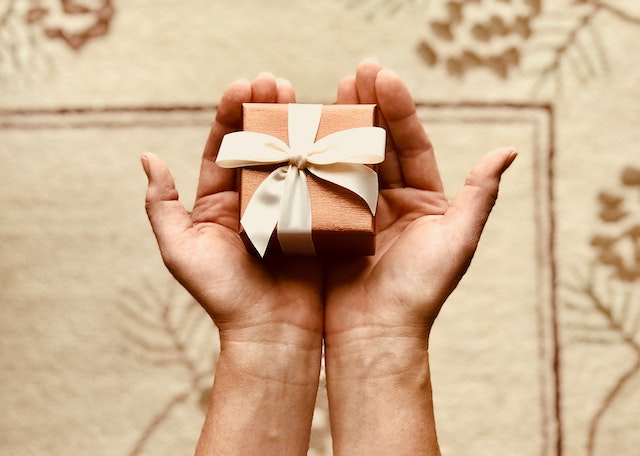 A person holding a brown box-wrapped gift.