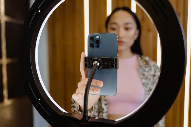 Uma garota gravando a si mesma com um anel de luz de um smartphone. 