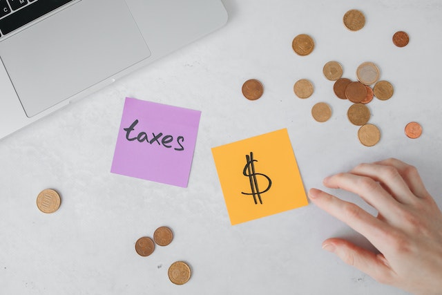 Sticky notes and coins on a table next to a laptop.