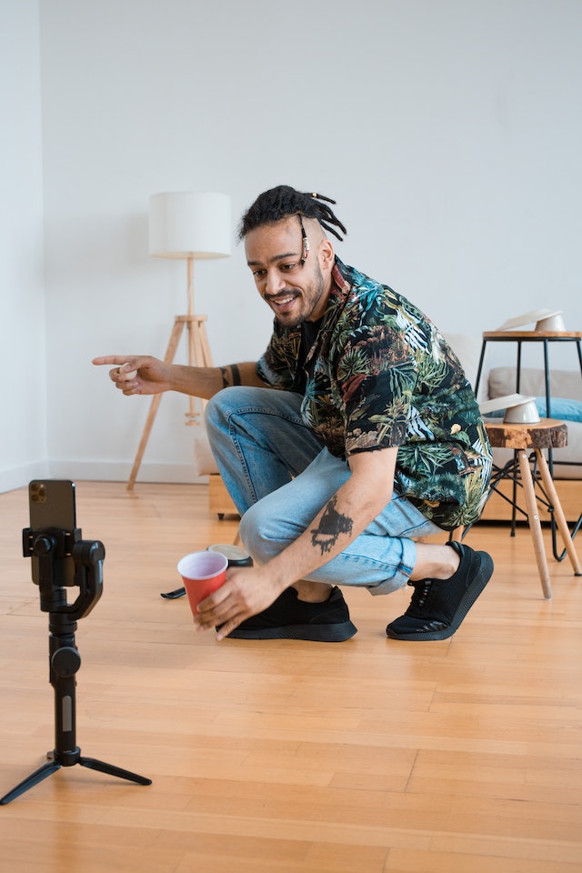 Um homem com uma camisa estampada e jeans gravando um vídeo para o TikTok.