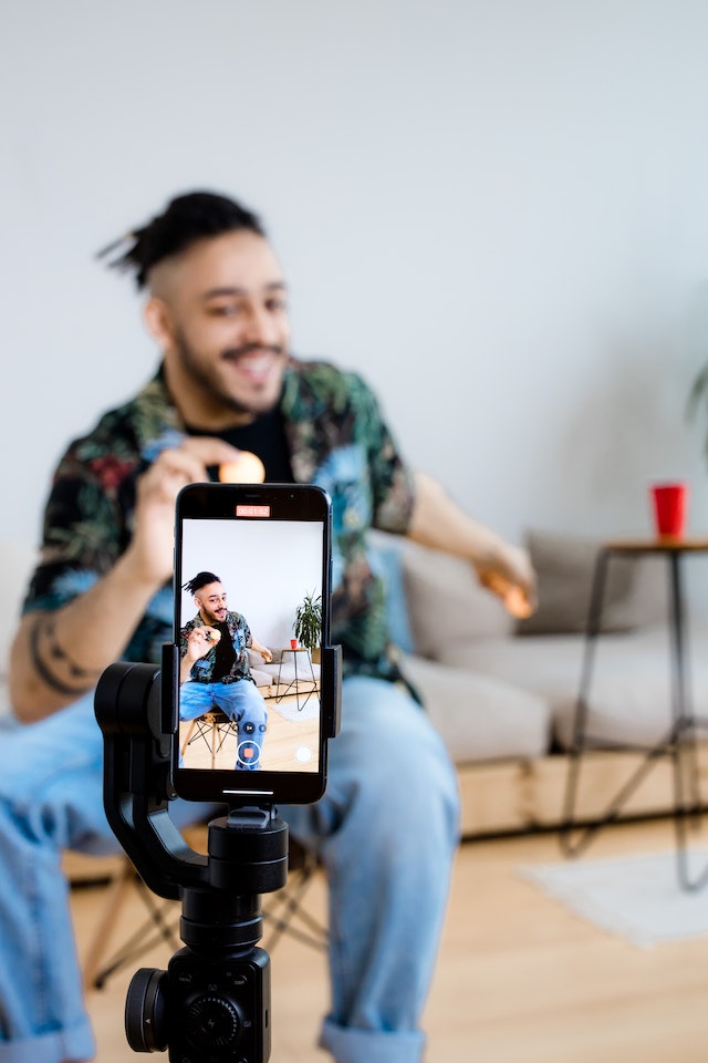 A man sitting and recording himself for a TikTok video. 