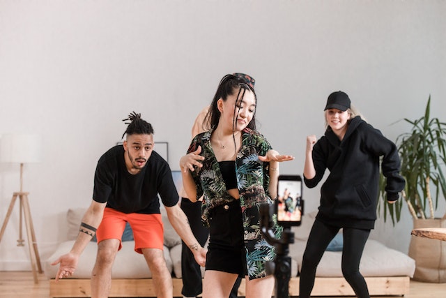 Un grup de oameni care dansează și înregistrează un videoclip pentru TikTok. 